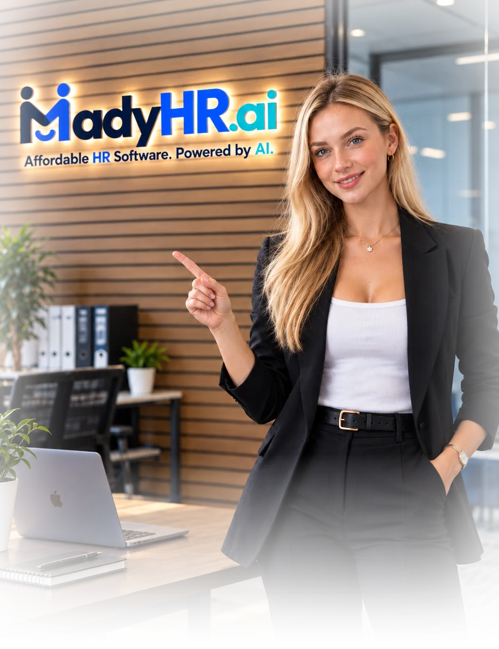 Mady in the MadyHR.ai office, pointing to the MadyHR.ai sign on the wall